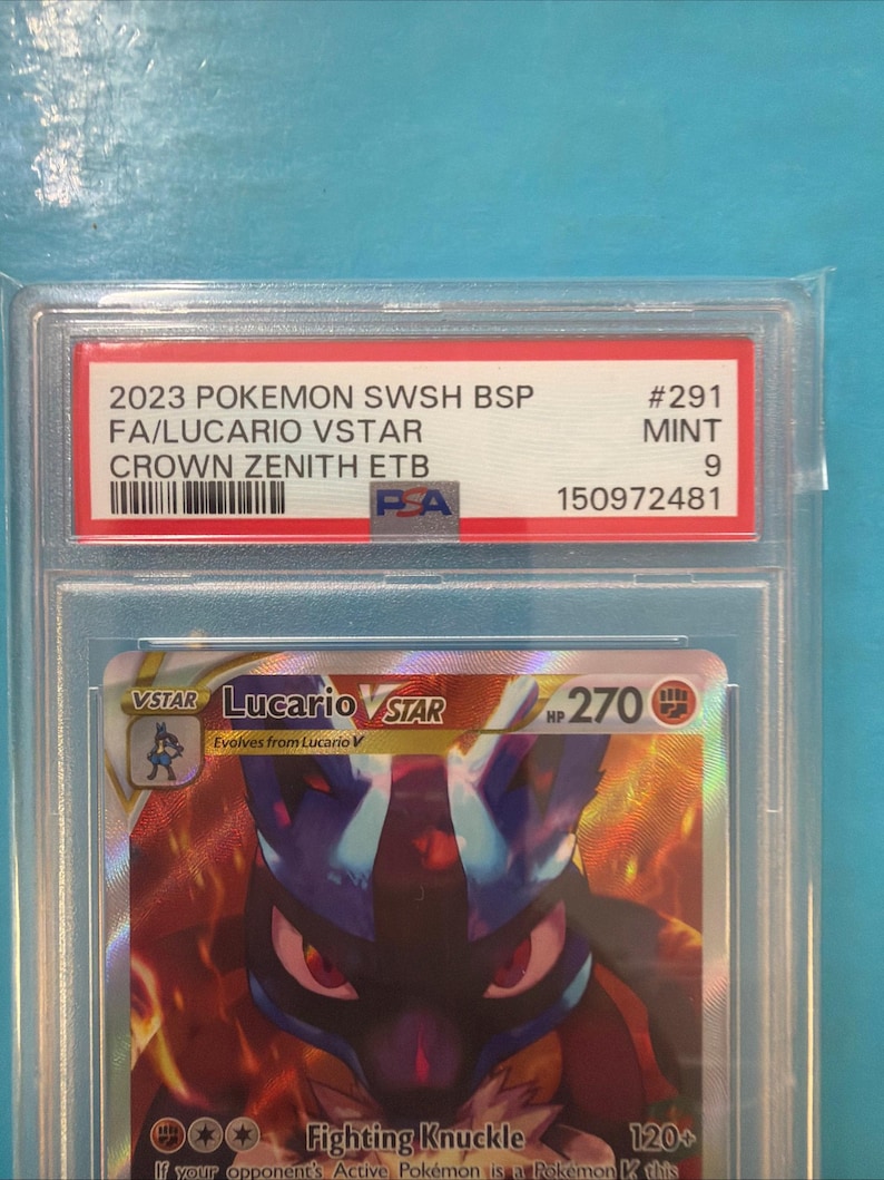 May include: A graded Pok&eacute;mon card featuring Lucario VSTAR. The card is encased in a protective holder with a red and white label that reads "2023 POKEMON SWSH BSP FA/LUCARIO VSTAR CROWN ZENITH ETB." The card is graded as Mint 9.