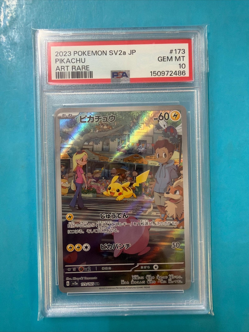 May include: A graded Pok&eacute;mon trading card featuring Pikachu, an Art Rare from the 2023 SV2a JP set. The card displays a colorful illustration of Pikachu with other characters. The card is encased in a protective holder.