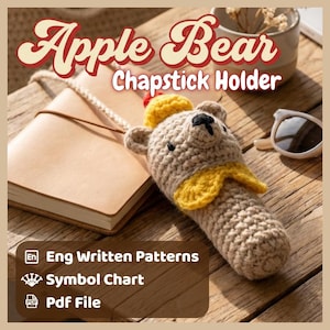 May include: Crocheted chapstick holder in the shape of a bear, with a yellow scarf and hat. The text "Apple Bear Chapstick Holder" is displayed above the bear. The holder is on a wooden surface next to a notebook and sunglasses.