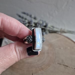 Puede incluir: Un anillo de plata con una piedra de luna rectangular y dos acentos de rosas en la banda.