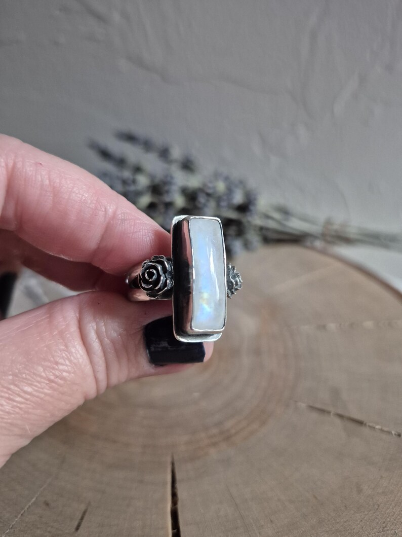 Puede incluir: Un anillo de plata con una piedra de luna rectangular y dos acentos de rosas en la banda.