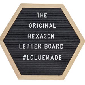 Puede incluir: Tablero de letras hexagonal con superficie de fieltro negro y marco de madera clara. El texto "THE ORIGINAL HEXAGON LETTER BOARD" se muestra en letras blancas, con el hashtag "#LOLUEMADE" en la parte inferior.