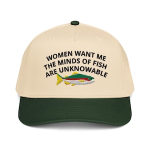 May include: A beige and dark green baseball cap with the text "WOMEN WANT ME THE MINDS OF FISH ARE UNKNOWABLE" and an embroidered fish graphic. The cap has a curved brim and a button on top.