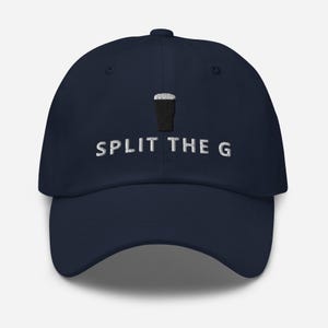 Puede incluir: Gorra de b&eacute;isbol azul marino con un gr&aacute;fico en blanco y negro de una pinta de cerveza negra y el texto bordado "SPLIT THE G". La gorra est&aacute; hecha de un material suave y tiene una visera curva.