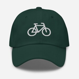 Puede incluir: Gorra de béisbol verde oscuro con un diseño de bicicleta bordado en blanco en la parte delantera. La gorra tiene una visera curva y una correa ajustable en la parte trasera. El diseño de la bicicleta es un contorno simple.