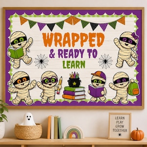 May include: A rectangular classroom bulletin board display featuring the text WRAPPED & READY TO LEARN in orange, purple, and green. The design includes six cartoon mummies, a stack of books, a pencil, and a banner with triangular flags.