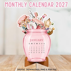 Puede incluir: Un calendario de frasco de vidrio rosa para enero de 2027, con artículos de costura como tijeras, un maniquí y carretes de hilo. El texto dice MONTHLY CALENDAR 2027, JANUARY y DIGITAL DOWNLOAD | PNG & PDF FILE. Se apoya sobre un soporte de madera.