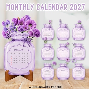 May include: A 2027 monthly calendar featuring purple glass vase illustrations. Each month is displayed on a separate vase graphic adorned with purple flowers and a tied cord. The large January vase sits on a wooden stand. Text includes MONTHLY CALENDAR 2027 and A HIGH-QUALITY PDF FILE.
