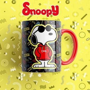 May include: A ceramic mug featuring Snoopy wearing sunglasses and a red hoodie with the word "Cool" on it. The mug has a black background with colorful geometric shapes and the word "Great" repeated. The handle is red, and the Snoopy logo is at the top.