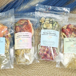 Puede incluir: Cuatro bolsas transparentes llenas de popurrí. Cada bolsa tiene una etiqueta con texto. Las bolsas contienen flores y hierbas secas. Las etiquetas dicen "Summer Vibes", "Summer Solstice", "Spring Blessings" y "Spring Fling".