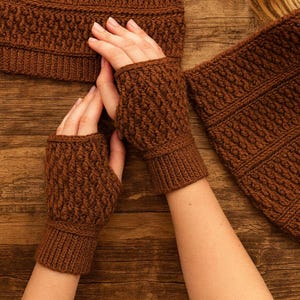 Peut inclure: Un ensemble marron composé de mitaines tricotées, d'un bonnet et d'une écharpe assortis. Les gants ont un poignet côtelé et un motif texturé sur la main. Le bonnet et l'écharpe ont également un motif texturé assorti. L'ensemble est en matière douce et chaude.