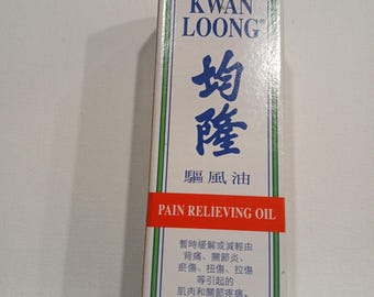 May include: Rectangular box of Kwan Loong Pain Relieving Oil. The box is white with green and red accents. The text on the box includes the brand name, product name, and other information in English and Chinese.