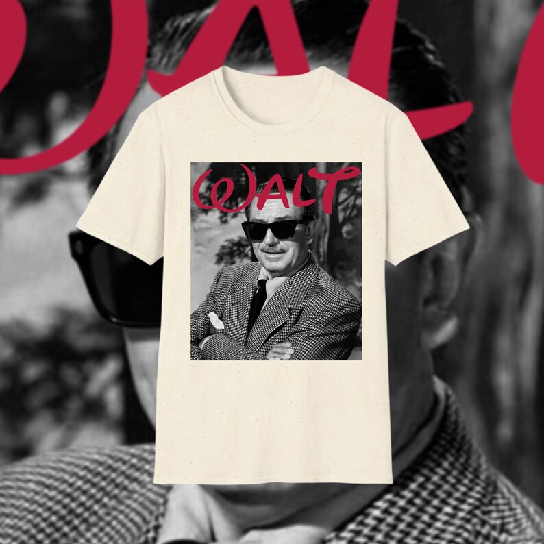 May include: A cream-coloured t-shirt with a black and white image of a man wearing sunglasses. The word "WALT" is printed in red cursive script above the image. The man in the image is wearing a patterned blazer and a tie.