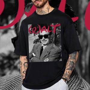 May include: Black t-shirt with a black and white image of a man in sunglasses and a suit. The word "WALT" is printed in red above the image. The shirt has a crew neck.