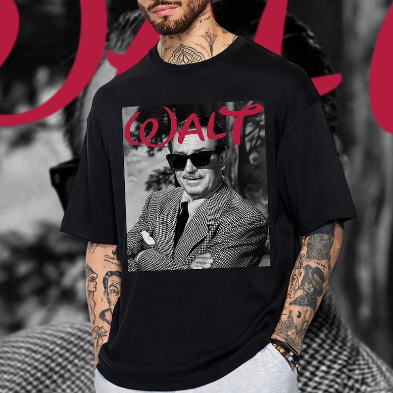 May include: Black t-shirt with a black and white image of a man in sunglasses and a suit. The word "WALT" is printed in red above the image. The shirt has a crew neck.