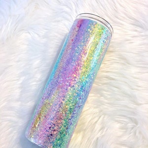 May include: A clear tumbler with a rainbow iridescent glitter design. The glitter is a mix of pink, purple, blue, and green.