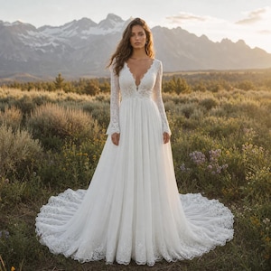 May include: A floor-length white wedding dress featuring long lace sleeves, a deep V-neckline, and a fitted bodice that transitions into a flowing, full-length skirt with a lace-trimmed hemline that spreads out across the ground.