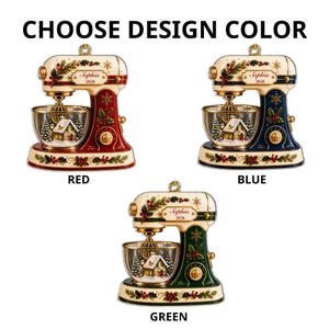 May include: Three stand mixer ornaments in red, blue, and green, each featuring a cream-colored top, gold accents, and a clear bowl containing a winter house scene. The text "Sophia 2026" is printed on the side of each mixer, with "CHOOSE DESIGN COLOR" above.