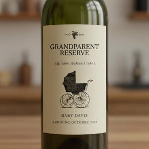 May include: A green wine bottle with a cream-colored label. The label reads "Grandparent Reserve" above the phrase "Sip now. Babysit later." A vintage baby carriage illustration is below the text. The label also includes "Baby Davis" and "Arriving October 2026."
