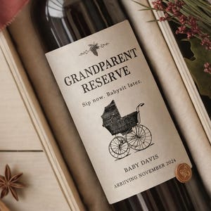 May include: A wine bottle with a label that reads "Grandparent Reserve" and "Sip now. Babysit later." The label features a vintage baby carriage illustration. The bottle is in a wooden box, tied with a burgundy ribbon.