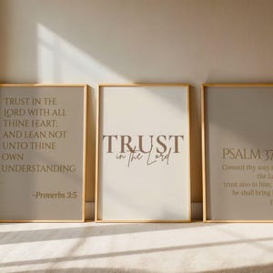 Può includere: Tre stampe artistiche incorniciate con cornici dorate. Le stampe presentano citazioni ispiratrici in una tavolozza di colori neutri. La prima stampa recita "Trust in the Lord..." La seconda dice "Trust in the Lord." La terza dice "Psalm 37:5."
