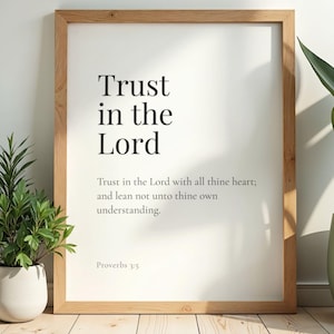 Puede incluir: Un cuadro enmarcado con el texto "Trust in the Lord" en un diseño minimalista. El cuadro incluye una cita de Proverbios 3:5. El marco es de madera clara y el fondo es blanco.