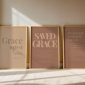 Könnte beinhalten: Drei gerahmte Kunstdrucke mit goldenen Rahmen. Die Drucke zeigen inspirierenden Text in einer neutralen Farbpalette. Der erste Druck lautet "Grace upon grace". Der zweite Druck lautet "Saved by Grace". Der dritte Druck lautet "My grace is sufficient for you."