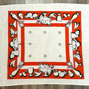 May include: A white tablecloth with a red border and a black and white design of fruit and flowers. The design includes pears, grapes, apples, pineapples, and flowers.