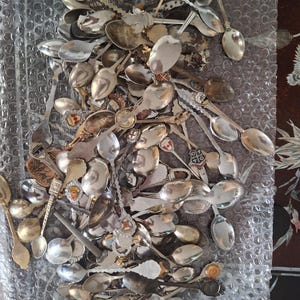 Puede incluir: Una colección de cucharas antiguas, muchas con mangos decorativos y diseños intrincados. Las cucharas están hechas de varios metales, incluyendo tonos plateados y dorados. Algunas cucharas presentan detalles de esmalte y escudos.