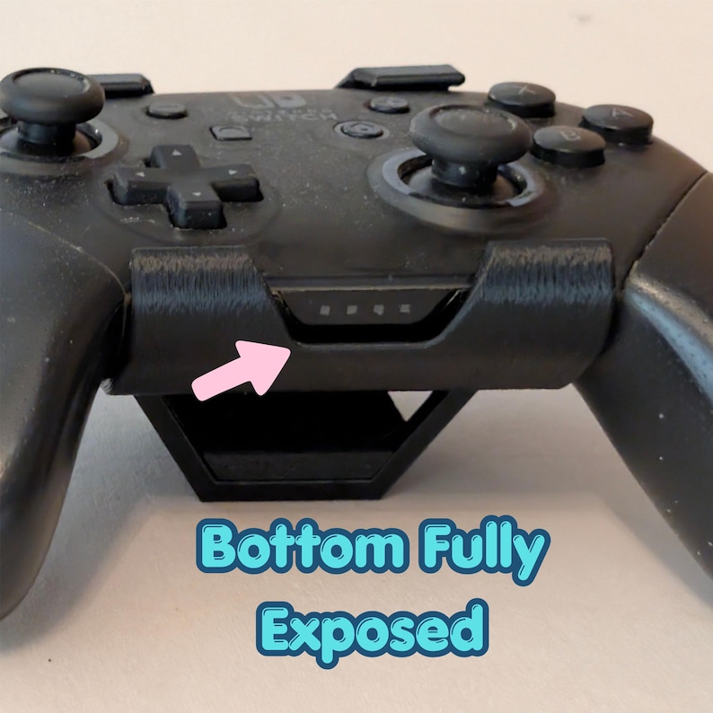 May include: Black video game controller with buttons, joysticks, and a directional pad. The controller has a built-in stand and a series of small indicator lights. The text "Bottom Fully Exposed" is visible.