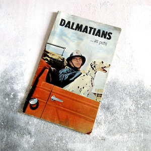 May include: A vintage book cover featuring a Dalmatian dog and a person in a firefighter's uniform. The book title is "Dalmatians... as pets".