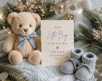 May include: A beige teddy bear with a light blue bow, a pair of light blue knitted baby booties, and a rectangular announcement card with the text: OUR Little Boy IS ON HIS WAY, ARRIVING DECEMBER 202X, decorated with a small blue heart.