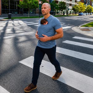 Peut inclure: Un t-shirt porte-b&eacute;b&eacute; bleu poussi&eacute;reux &agrave; manches courtes dot&eacute; d'une poche int&eacute;gr&eacute;e sur la poitrine contenant un petit nourrisson. Le t-shirt est associ&eacute; &agrave; un pantalon bleu marine fonc&eacute; et &agrave; des chaussures en daim marron pour le portage.