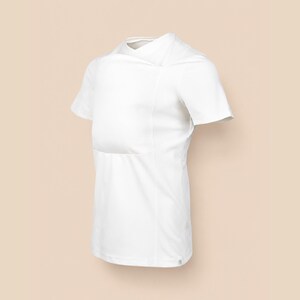 May include: A solid white short-sleeved shirt featuring a unique overlapping fabric panel across the chest and shoulder area. The garment has a crew neckline, a straight hemline, and a clean, seamless construction throughout the front torso.