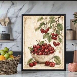 May include: A framed print featuring a watercolor illustration of cherries. A white bowl filled with ripe red cherries sits below a branch with more cherries and white blossoms. The background is a light beige with decorative borders.