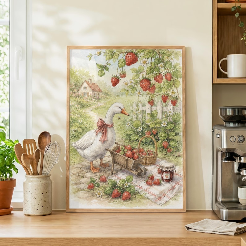 May include: A framed print of a goose with a pink bow, a wheelbarrow, and a basket filled with strawberries. The artwork depicts a charming rural scene with a house, white picket fence, and strawberry plants. A jar of jam sits on a checkered cloth.