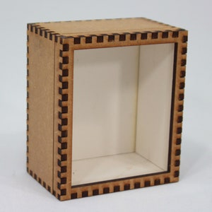 以下が含まれることがあります： 透明な前面パネルが付いた小さな木製のディスプレイボックス。ボックスは、エッジの周りに装飾的なレーザーカットの境界線があります。
