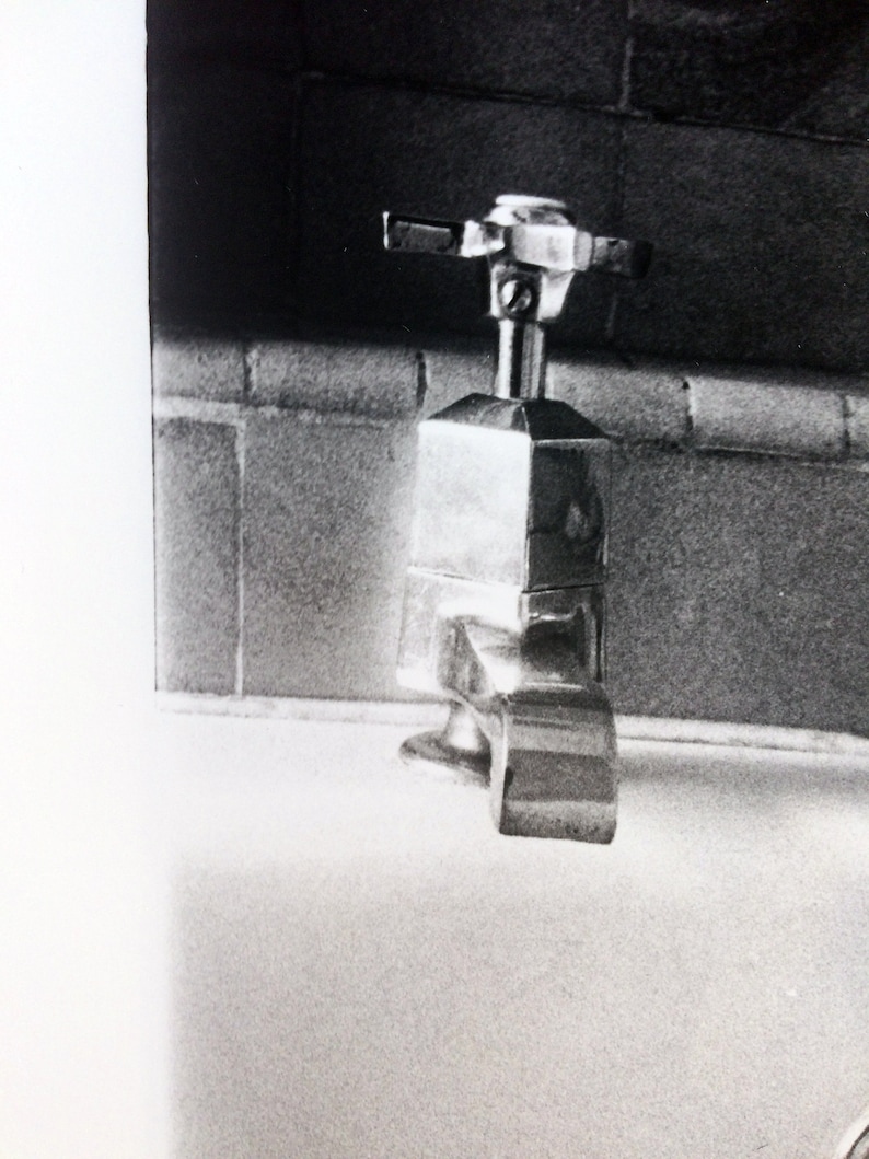 Peut inclure: Un robinet en argent avec une base carr&eacute;e et une poign&eacute;e en forme de croix. Le robinet est mont&eacute; sur un comptoir blanc.