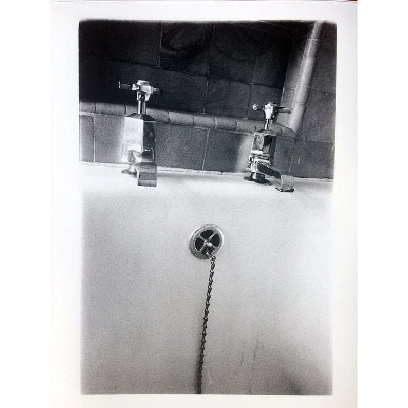 Peut inclure: Une photographie en noir et blanc d'une salle de bain vintage avec deux robinets chrom&eacute;s et un bouchon de vidange &agrave; cha&icirc;ne.