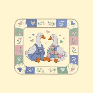 Puede incluir: Cuadrado bordado con dos gansos enfrentados, rodeados de corazones y detalles florales. Uno lleva un peto azul, el otro un vestido de retazos. El borde tiene un diseño de retazos con corazones y flores.