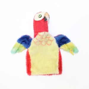 May include: A colorful plush parrot puppet with red, yellow, blue, and green feathers. The puppet has a large head with a black beak and a green eye. The puppet is designed to be worn on a hand.