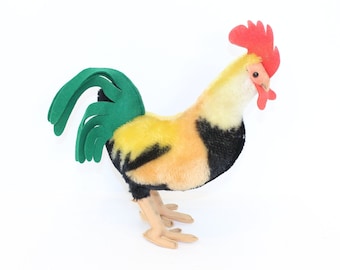 May include: A plush toy rooster with a yellow, black, and orange body, green tail feathers, and a red comb.