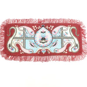 Può includere: Tessuto rettangolare rosso con un design ricamato. Il motivo centrale presenta un motivo azzurro e bianco con accenti rosa e neri. I bordi sono rifiniti con una frangia rossa.