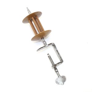 May include: An antique yarn swift with a clamp base. The swift features a wooden spool design with four vertical rods and two circular discs. The clamp is made of metal and has a screw mechanism for securing it to a surface.