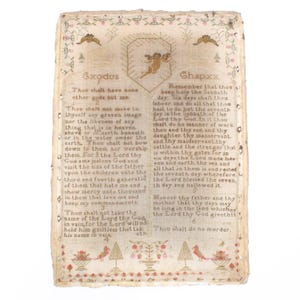 以下が含まれることがあります： 聖書のテキストが刺繍されたヴィンテージサンプラー。十戒も含まれています。サンプラーはクリーム色の生地に茶色の背景、花柄の縁取りが施されています。