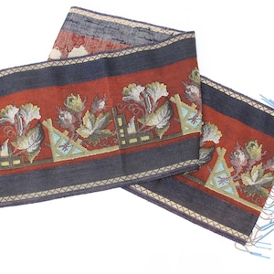 May include: A red, blue and cream woven fabric trim with a floral pattern and fringe. The trim has a geometric design and is perfect for adding a touch of elegance to any project.