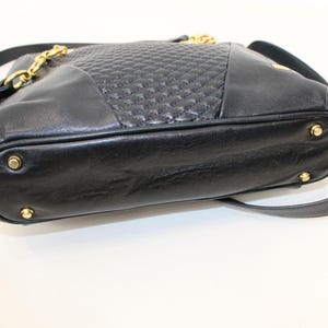 May include: Black leather shoulder bag with a quilted center panel and gold-tone chain and hardware. The bag has a long shoulder strap and a tassel detail. The bottom of the bag has four gold-tone feet.