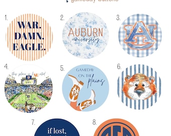 May include: A set of eight Auburn gameday buttons with diverse designs. The buttons feature text such as "War Damn Eagle," "Auburn University," and "Gameday on the Plains." Includes the Auburn logo, a tiger, and a football stadium.