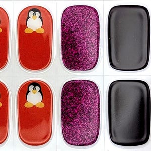 Puede incluir: Pegatinas de arte de uñas con diversos diseños. Los diseños incluyen magenta brillante, morado liso, negro y rojo con una ilustración de pingüino. Las pegatinas son rectangulares con bordes redondeados.
