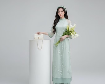 Femmes vietnamiennes modernes Ao Dai avec quatre panneaux brodés de motifs floraux, manches bouffantes, accents d'ailes de fée, tissu en soie traditionnel